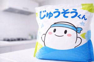 重曹の袋「じゅうそうくん」が画面いっぱいに写り、奥にレンジフードがぼんやり見えるキッチンのイメージ